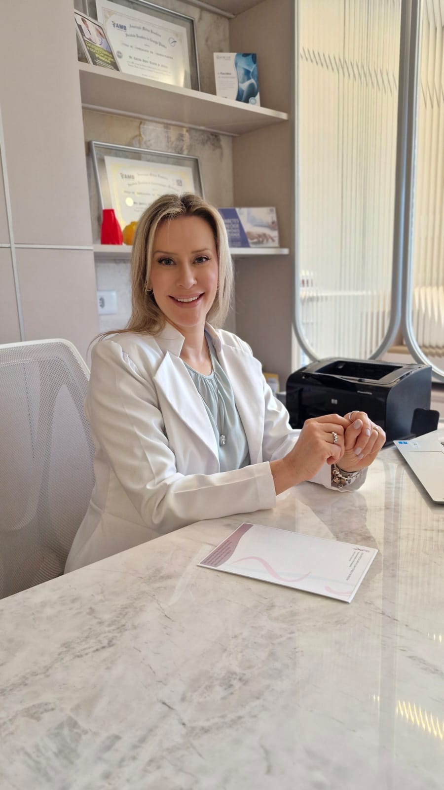Dra. Patrícia Zeni em seu consultório, sentada à mesa